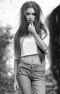 A cheerful woman in high-waisted jeans and a flowing blouse posing confidently outdoors against a city backdrop.