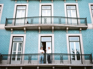 two men standing on black railings in blue concrete building
