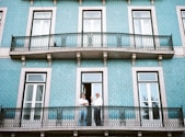 two men standing on black railings in blue concrete building