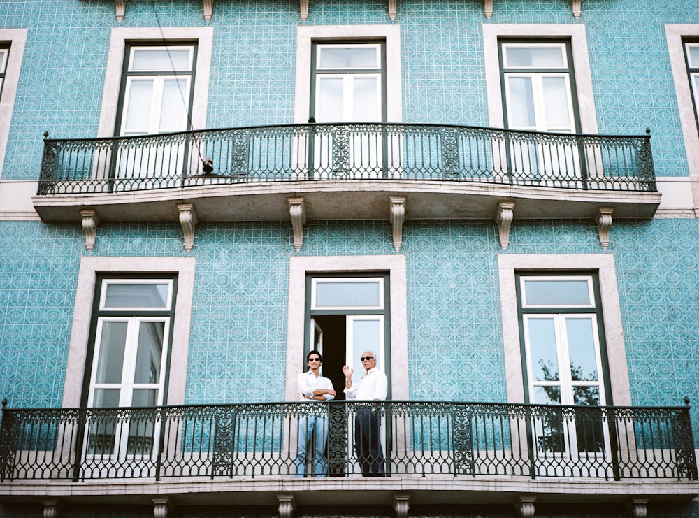 two men standing on black railings in blue concrete building