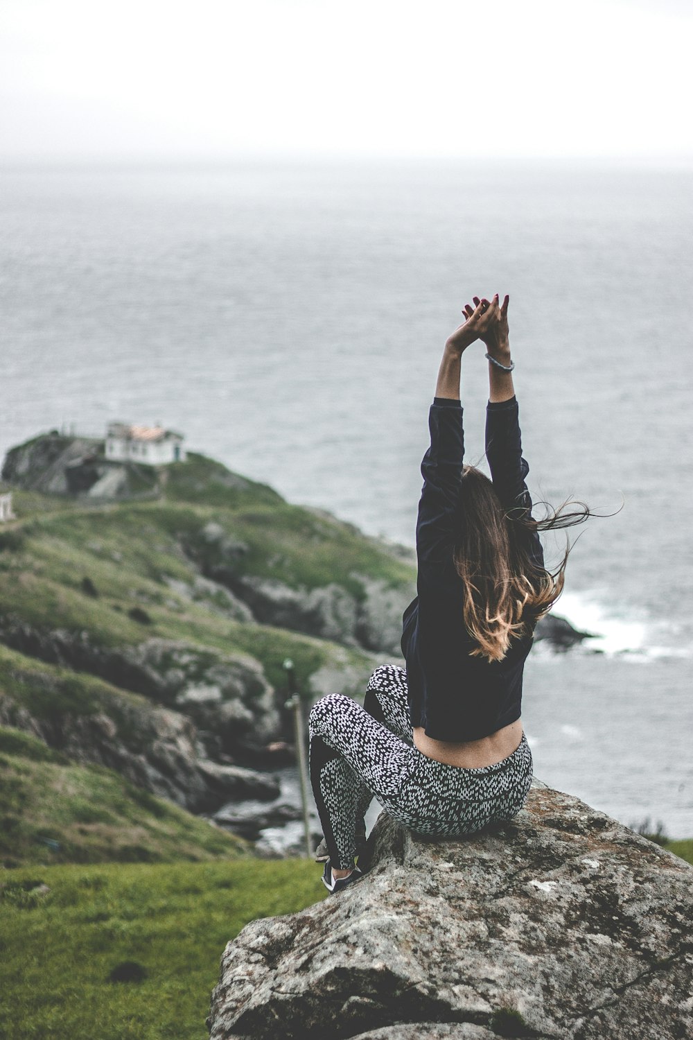 woman sitting on stone formation near cliff during daytime