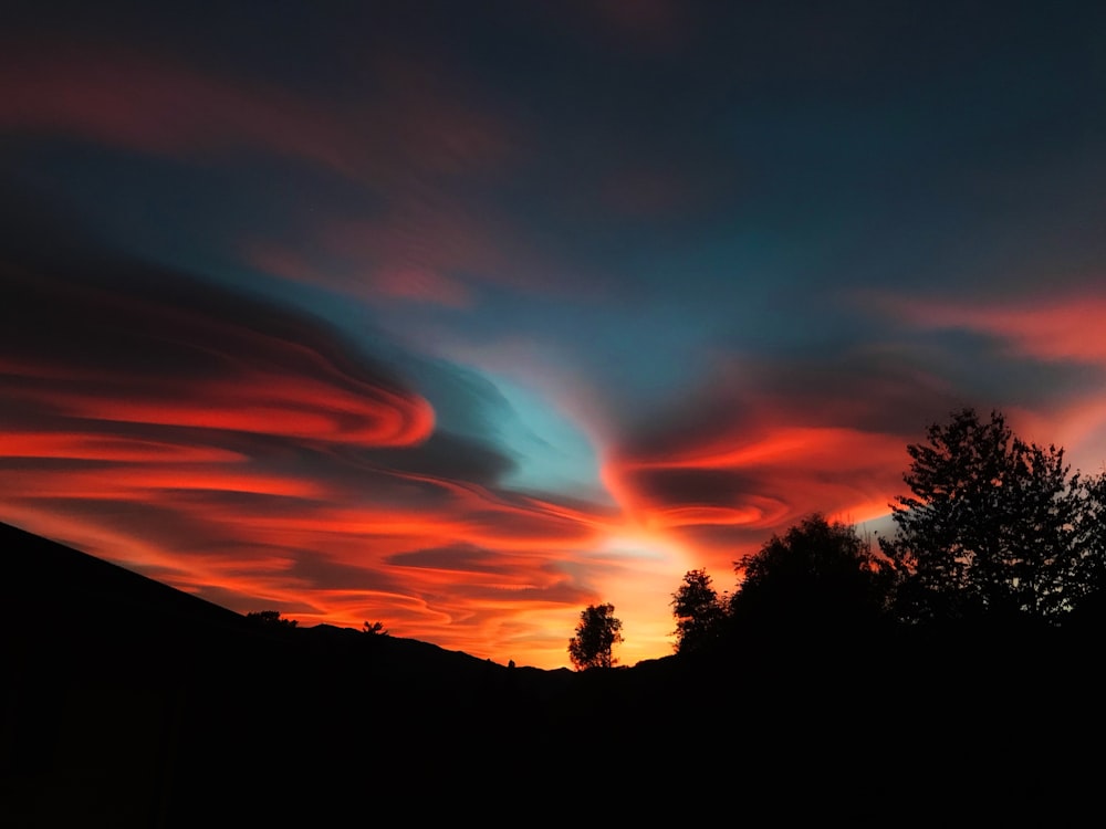 um céu vermelho e azul com nuvens e árvores