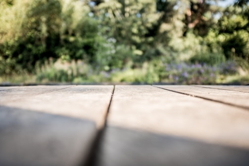 Close-up of hands installing wooden deck planks outdoors.