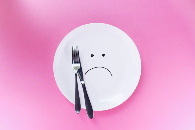 silver fork and knife on plate with unhappy smiley face