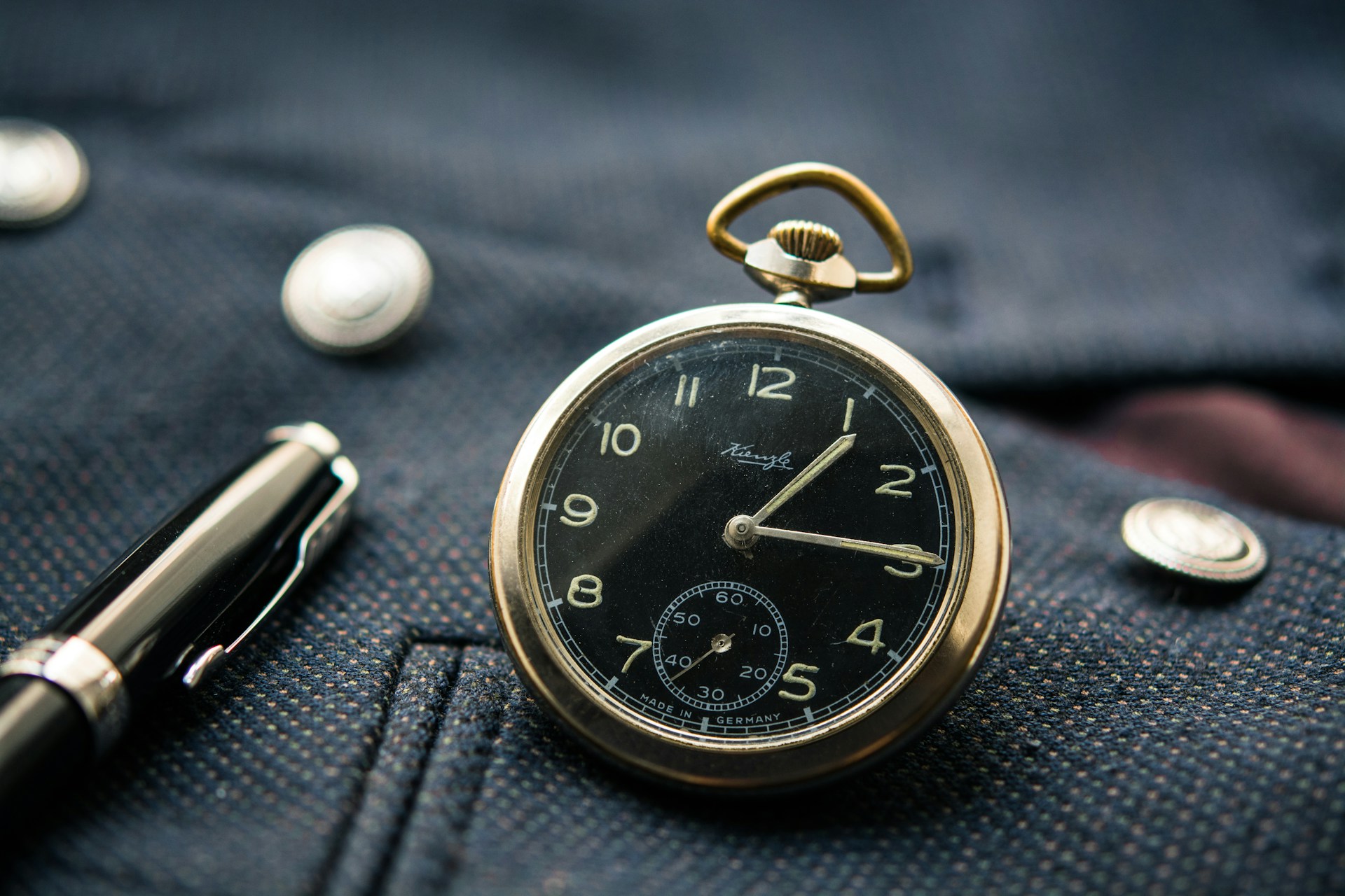 round silver-colored and black pocket watch displaying 1:15