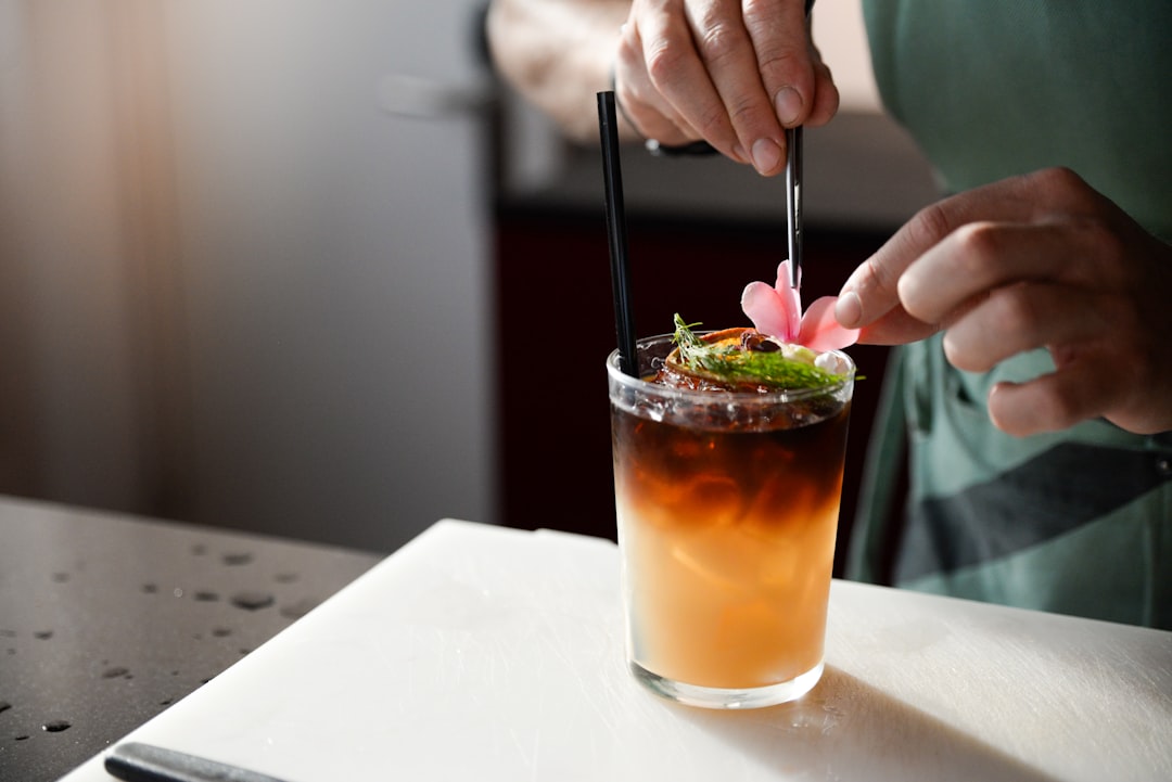 person making drink with flower petals, Italian craft bartender creates a customized drink with floral arrangements.