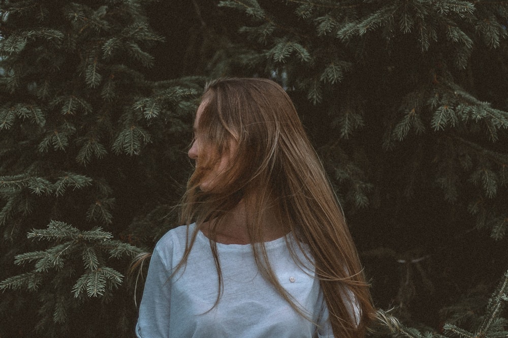 Mujer con camisa blanca cerca de un árbol