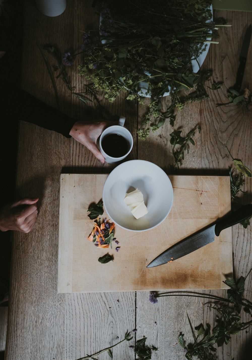 person holding mug beside plate on chopping board