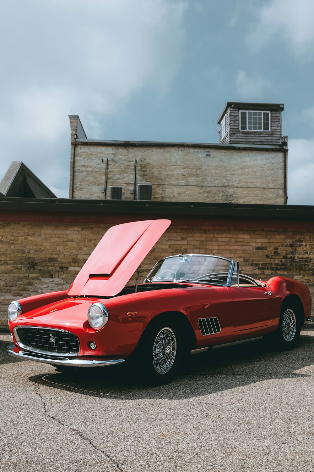 red convertible coupe parking near wall