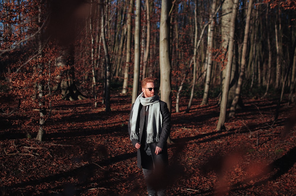 man wearing scarf standing under trees