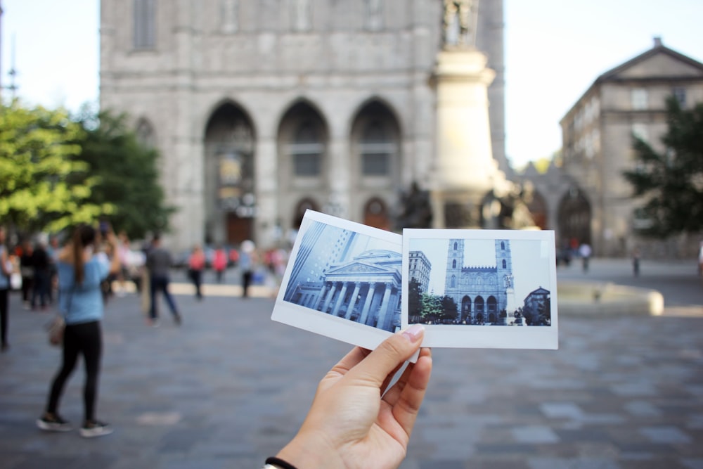 person holding two photo of buildings