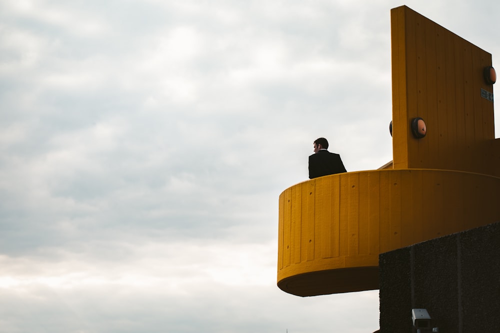 man standing on building under cloudy sky