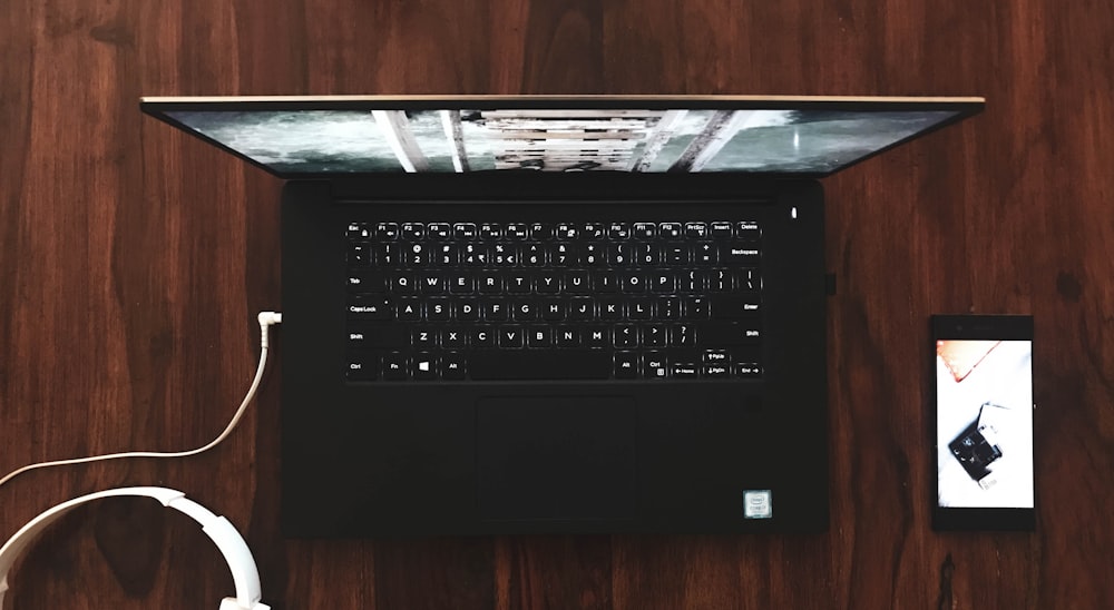 black and gray laptop computer turned on on wooden surface