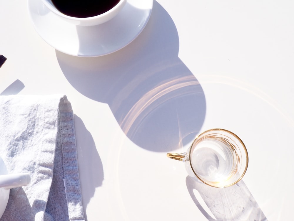 clear glass mug beside coffe