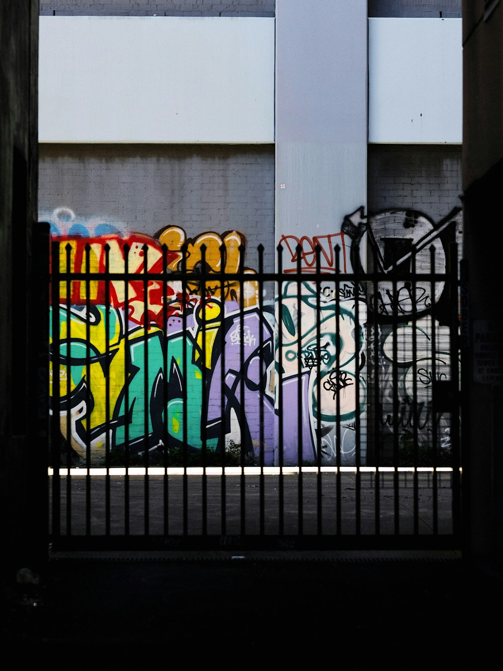 black metal fence near graffiti filled wall