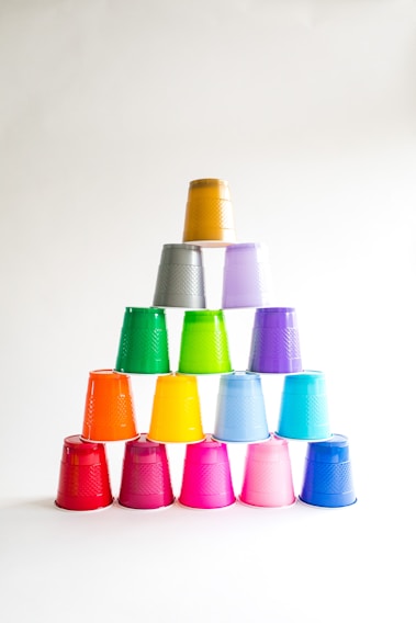 A close-up of vibrant plastic water buckets stacked neatly, showcasing their sturdy design and bright colors.