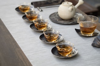 multiple clear drinking glasses with tea on gray surface