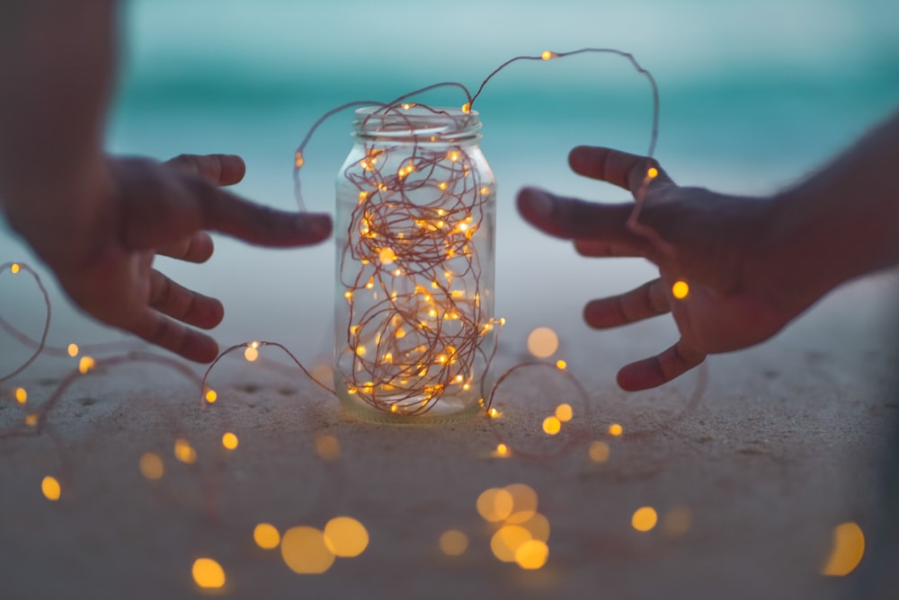 bokeh photography of lighted string lights inside Mason jar