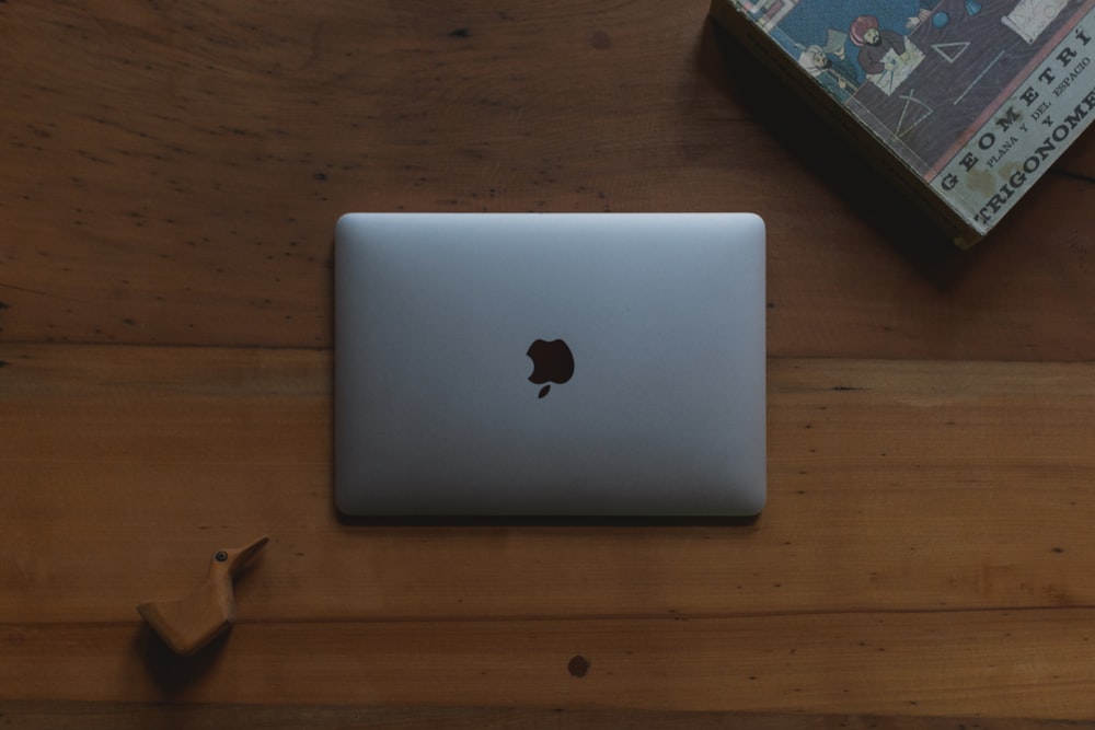 MacBook prateado na mesa de madeira marrom