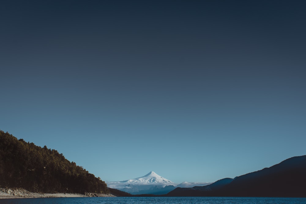 body of water near mountain during daytime