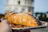 A warm pastizzi held in hand with the NYC skyline softly blurred in the background.