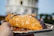 A warm pastizzi held in hand with the NYC skyline softly blurred in the background.