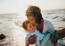 photo of mother and child beside body of water