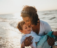 photo of mother and child beside body of water