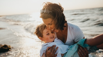 photo of mother and child beside body of water