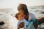 photo of mother and child beside body of water