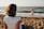 woman watching child playing on beach during daytime