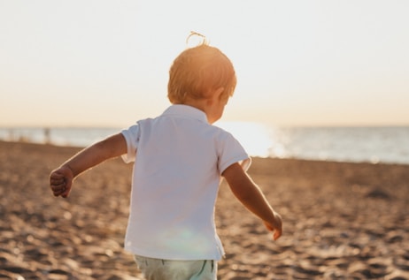 boy standing on sand near sea