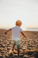 Children playing barefoot in soft sand, sunlight filtering through nearby trees.