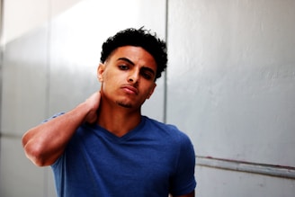 man standing holding neck in V-neck T-shirt