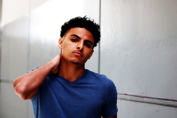 man standing holding neck in V-neck T-shirt