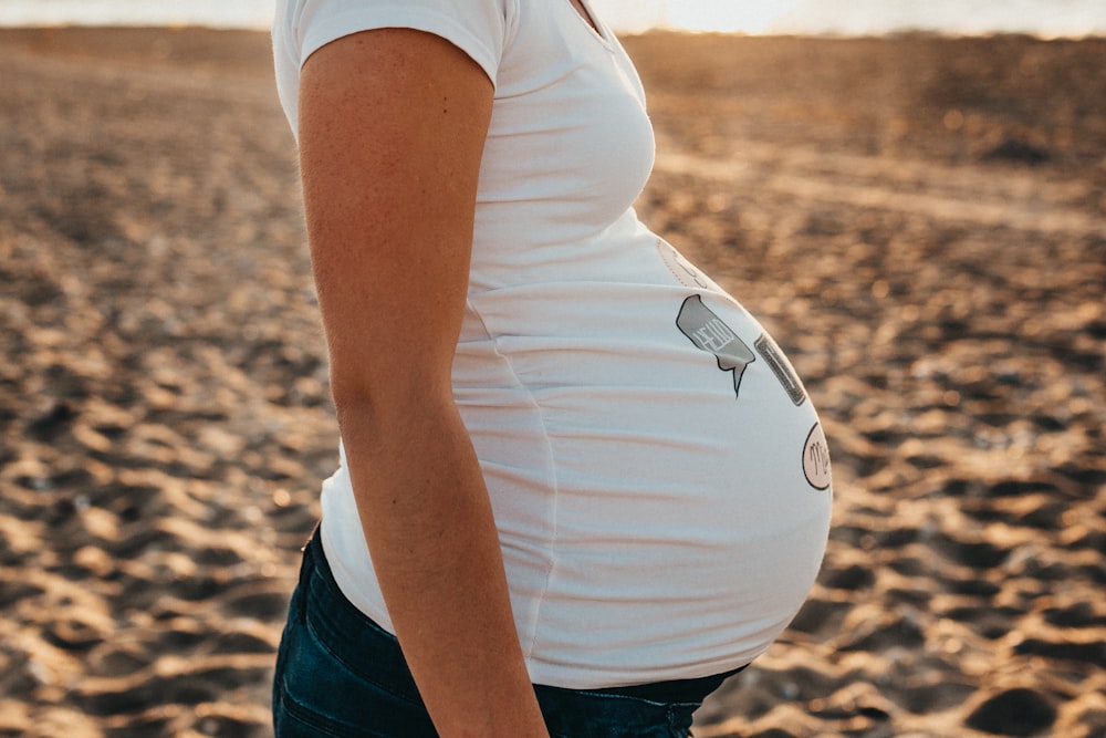 mujer embarazada de pie sobre la arena
