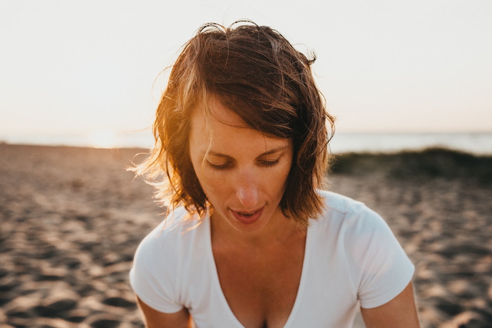 donna seduta sulla sabbia vicino alla riva del mare