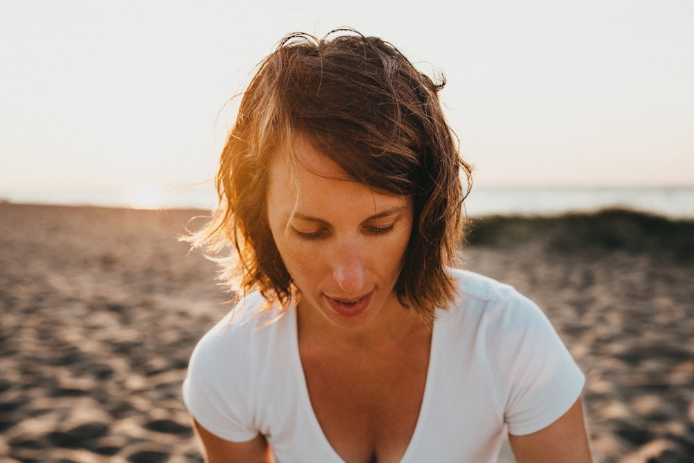 femme assise sur le sable près du rivage de la mer