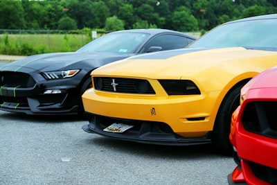 parked yellow ford mustang coupe and black ford teams background