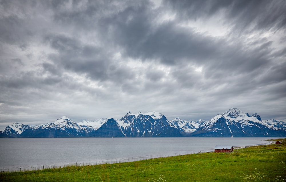 cuerpo de agua junto a la montaña cubierta de nieve bajo el cielo nublado gris