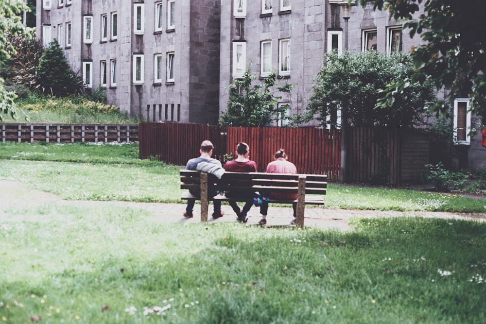 Tagsüber sitzen drei Personen auf einer Parkbank