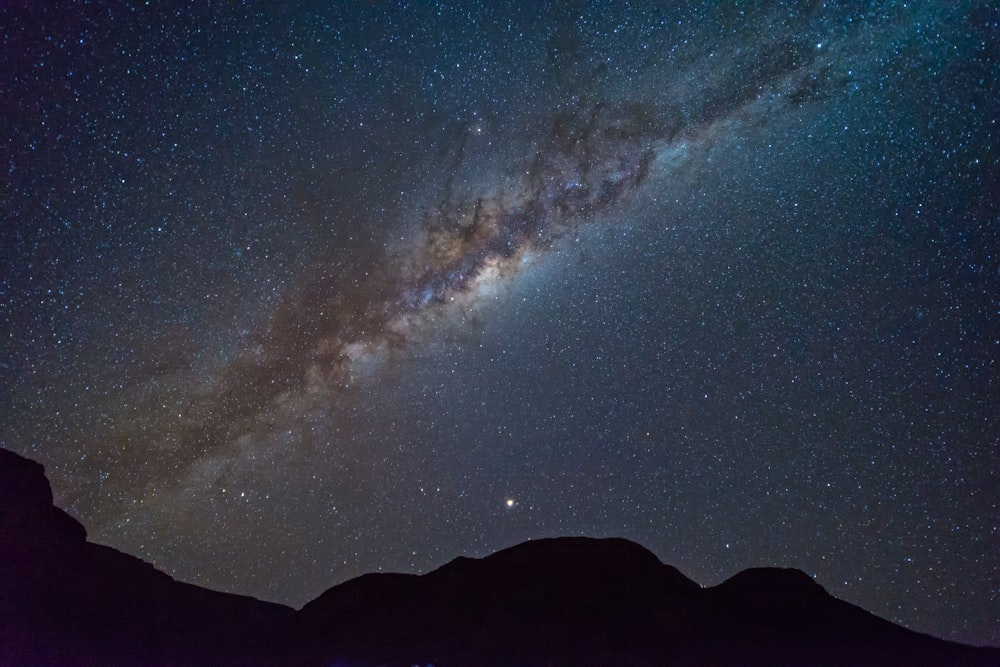 星雲の夜空の下の山のシルエット写真