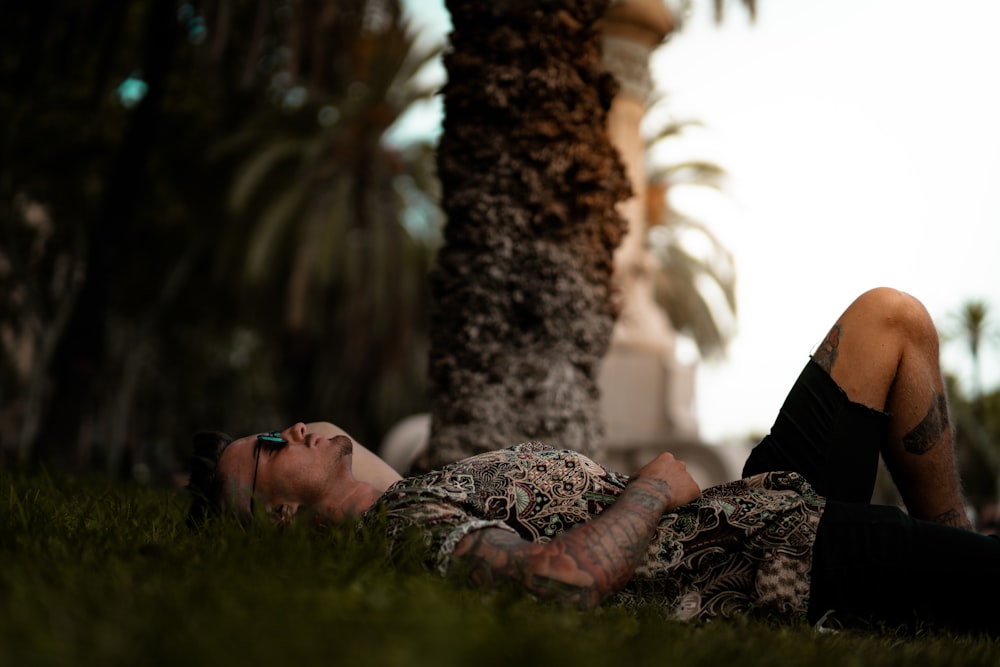 man in brown shirt lying on green grass