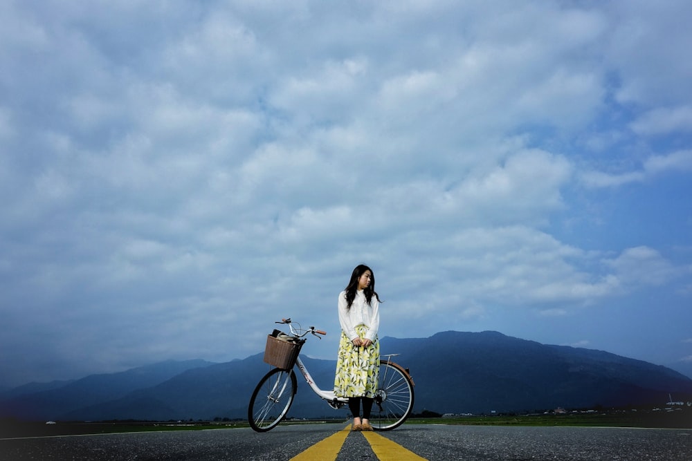 道路で自転車の横に立つ女性