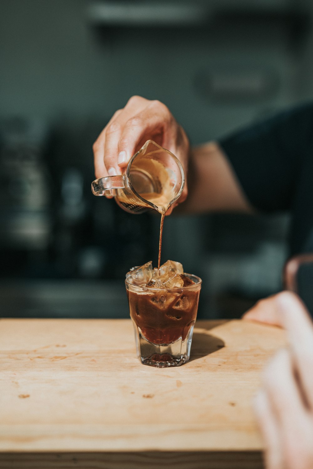 Person, die Kaffee auf Steinglas gießt