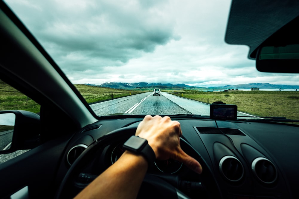 Pessoa dirigindo carro perto do veículo sob nuvens Nimbus