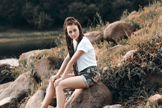 woman in white T-shirt sitting on rock