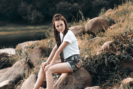 woman in white T-shirt sitting on rock