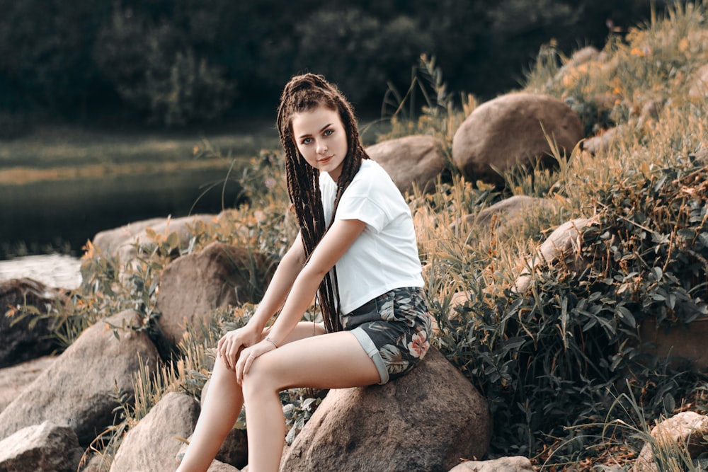 woman in white T-shirt sitting on rock