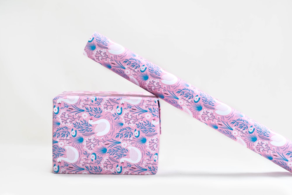 Papel de regalo floral rosa, blanco y azul apoyado en una caja envuelta